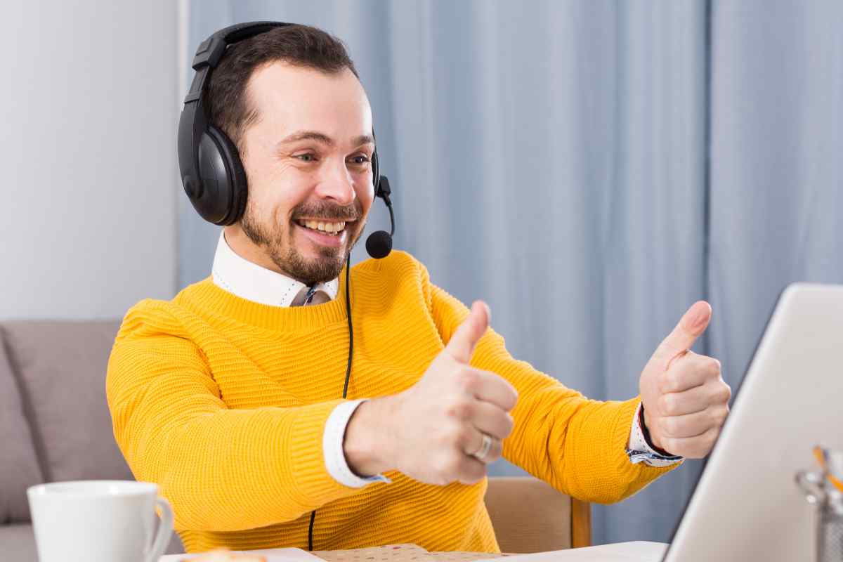 un ragazzo sorridente con i pollici in su mentre segue evento online sul portatile